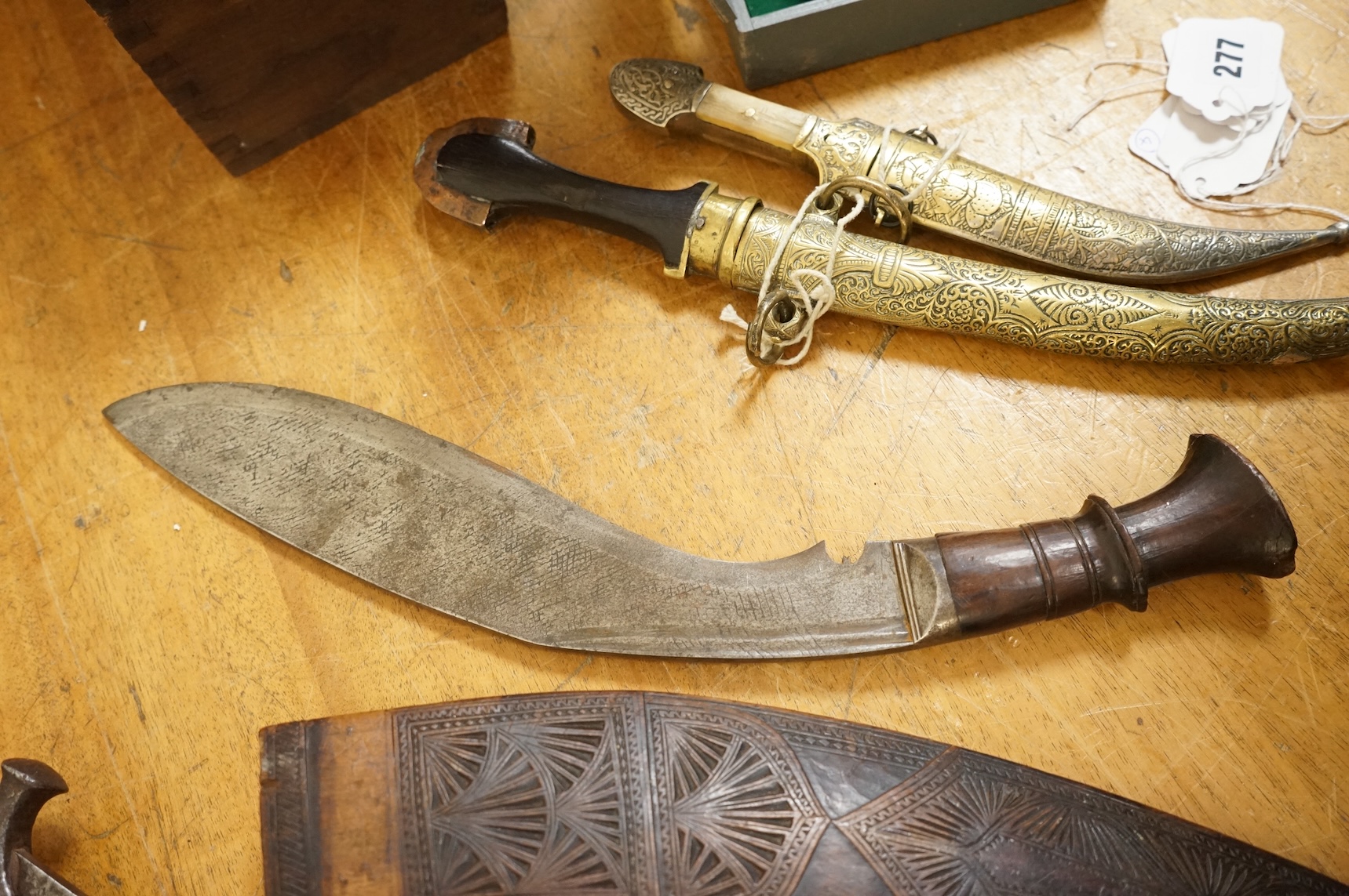 An Indian sword tulwar, the iron hilt with traces of chiselled and inlaid decoration, together with a kukri in its wooden scabbard, a Syrian jambya and a Moroccan jambiya (4)